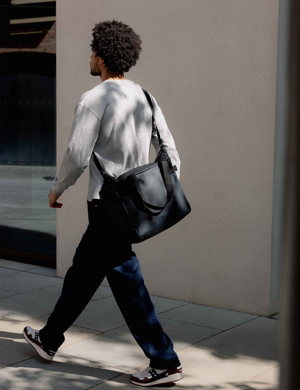 Midnight blue laptop tote bag carried by side handles with adjustable strap