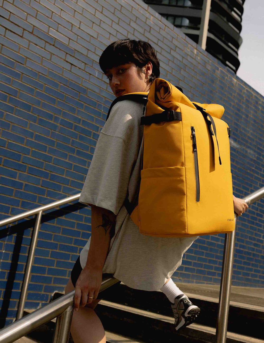 Yellow roll-top backpack with black roll-top strap and back padding