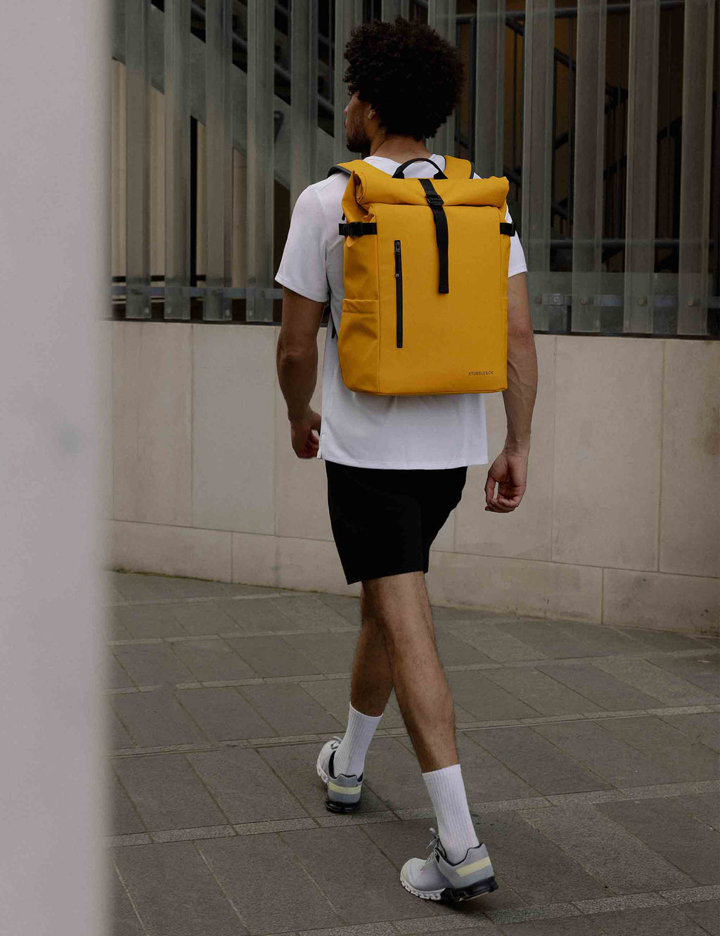 Yellow roll-top backpack worn on back with black shoulder straps