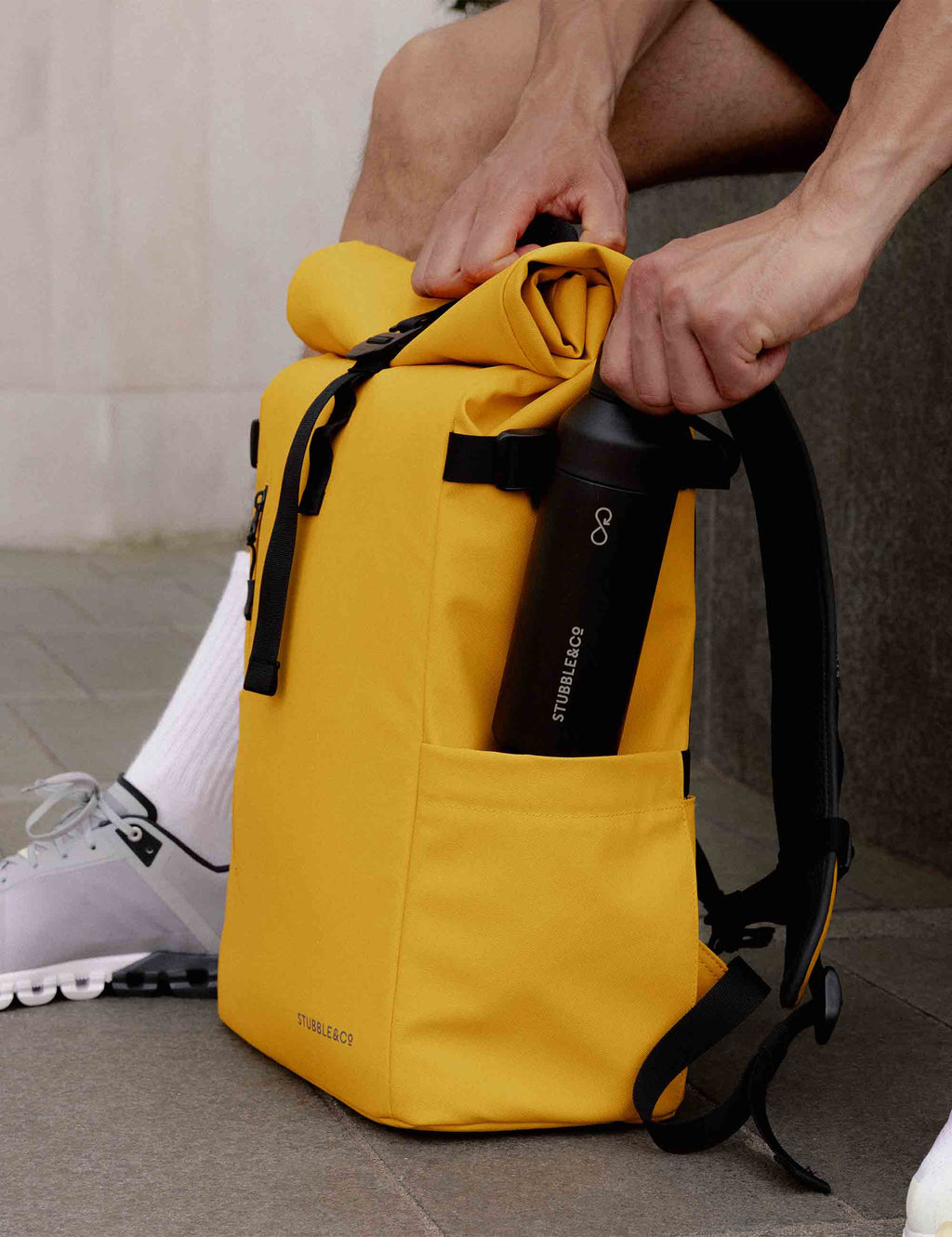 Yellow roll-top backpack with black shoulder straps and cinch roll-top closure