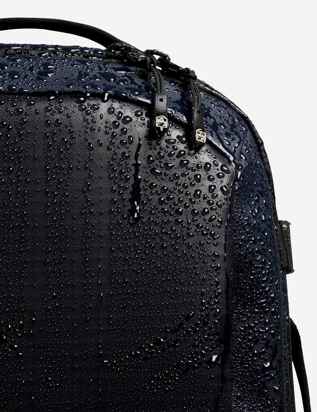 Midnight blue backpack fabric with visible water droplets on textured surface