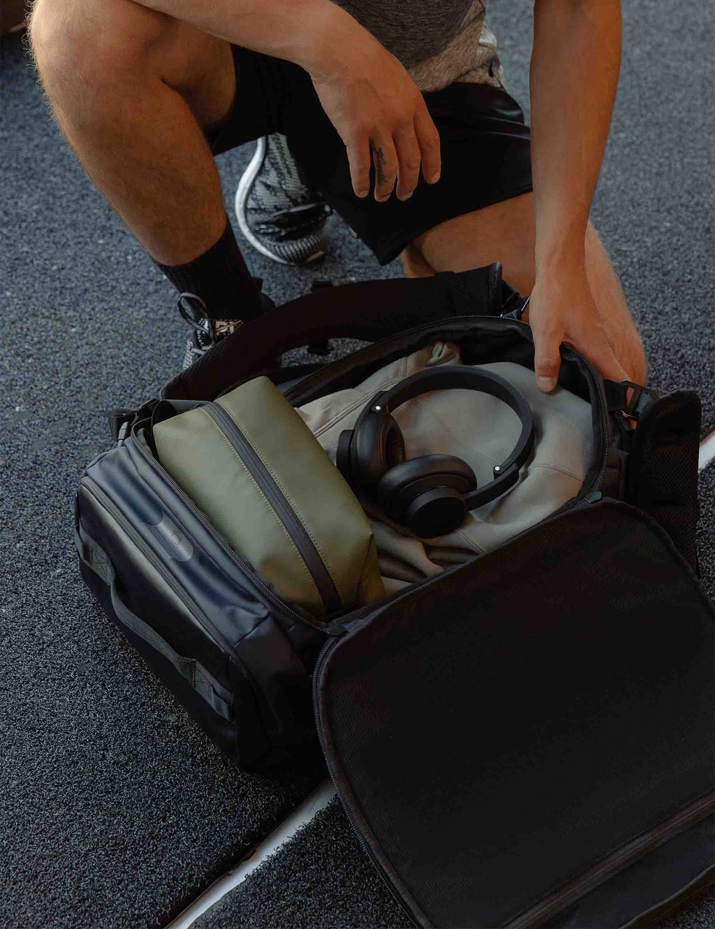 Dark blue 30L kit bag, open top showing interior pockets and headphones