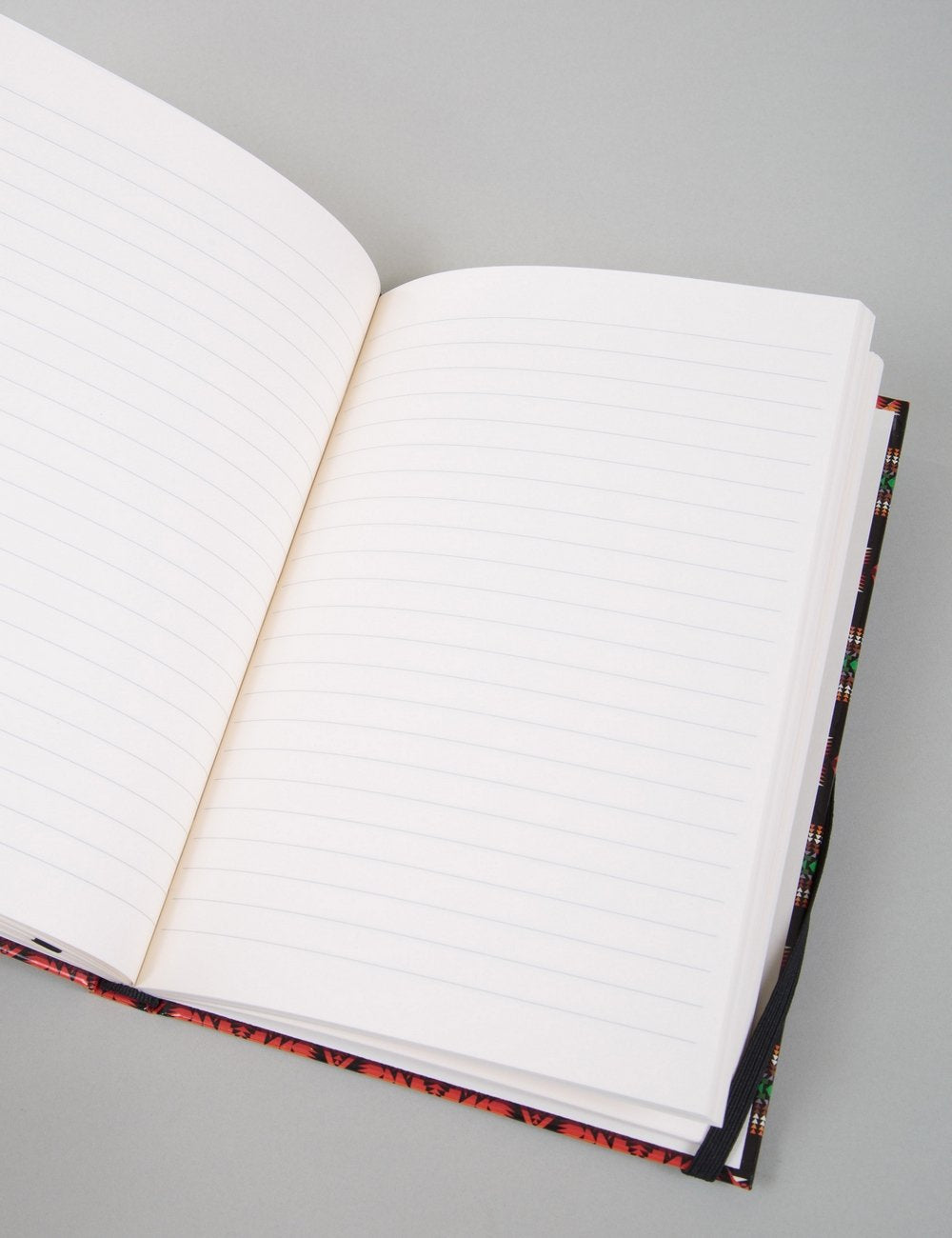 Open lined notebook showing blank white ruled pages and patterned black cover edge