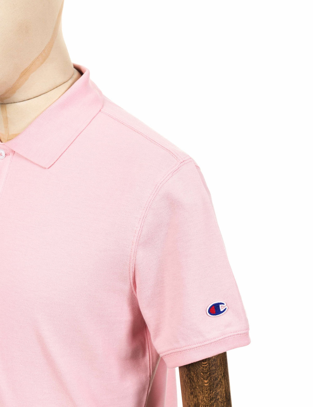 Pink polo shirt sleeve with embroidered logo near the hem