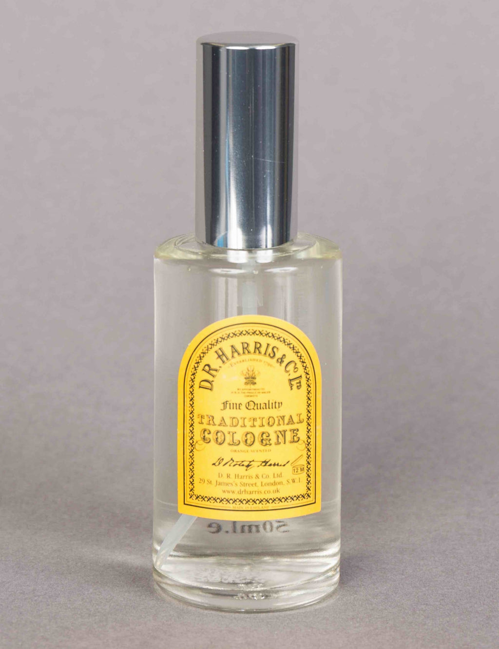 Traditional cologne spray bottle with silver cap, clear glass, gold label