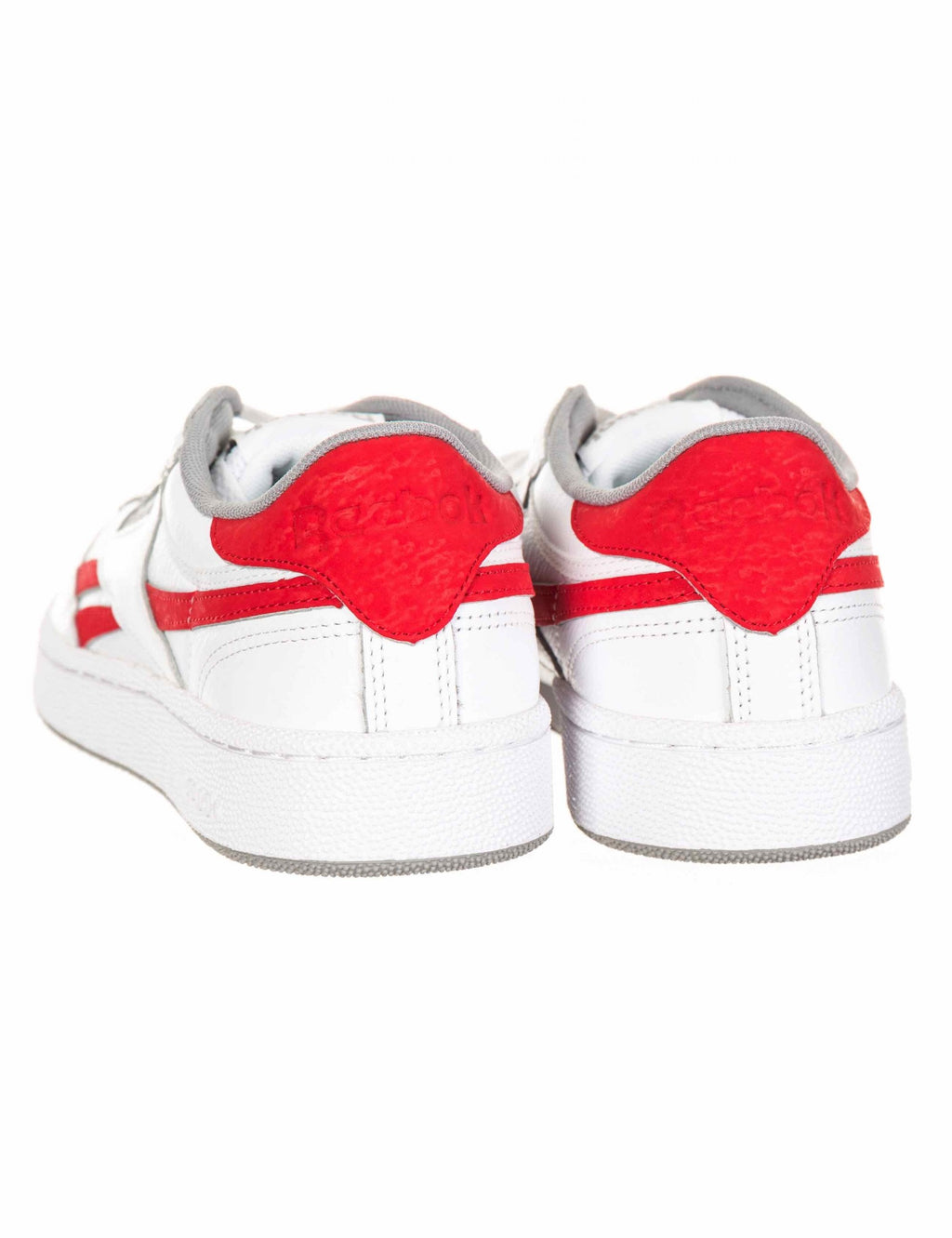 Pair of white trainers with red heel overlays and gray inner lining