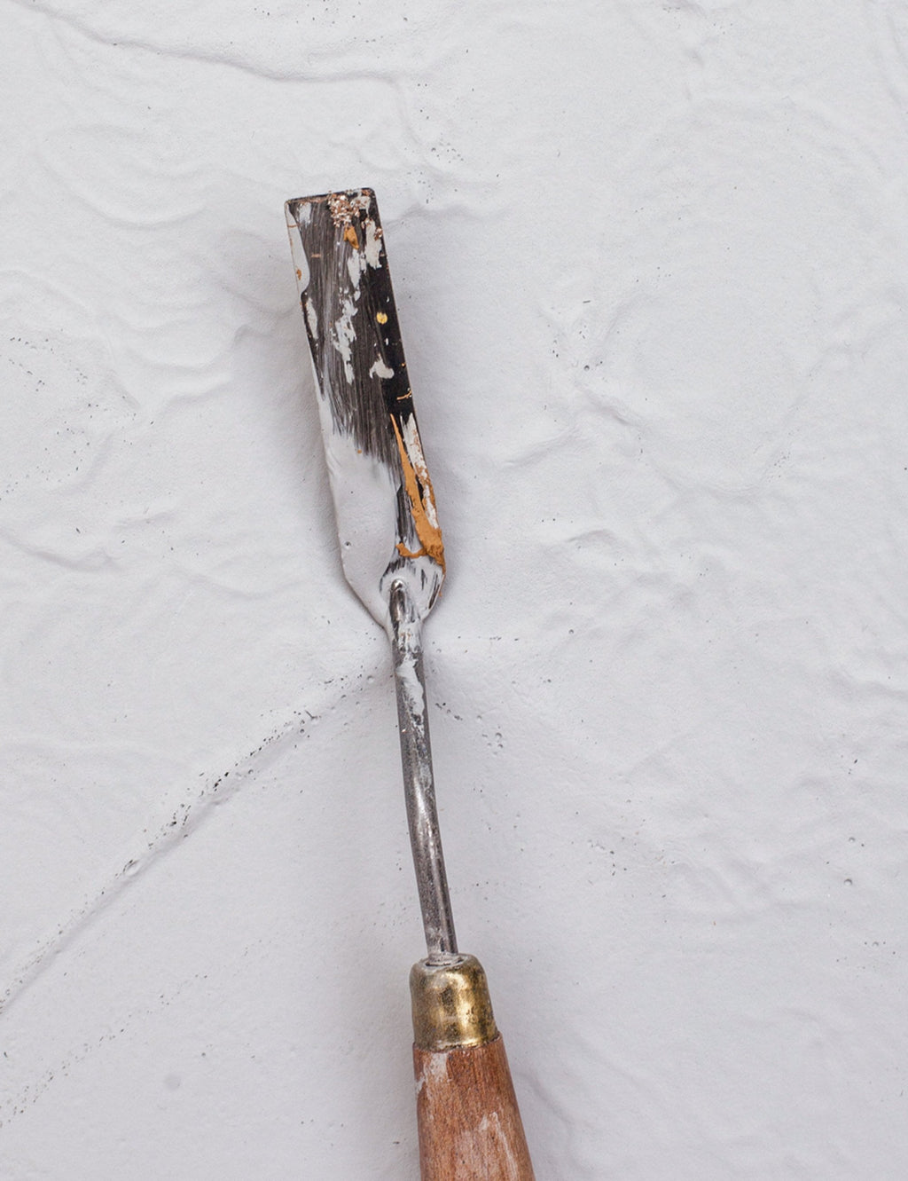 Paintbrush coated with grey texture-effect paint on bristles and handle