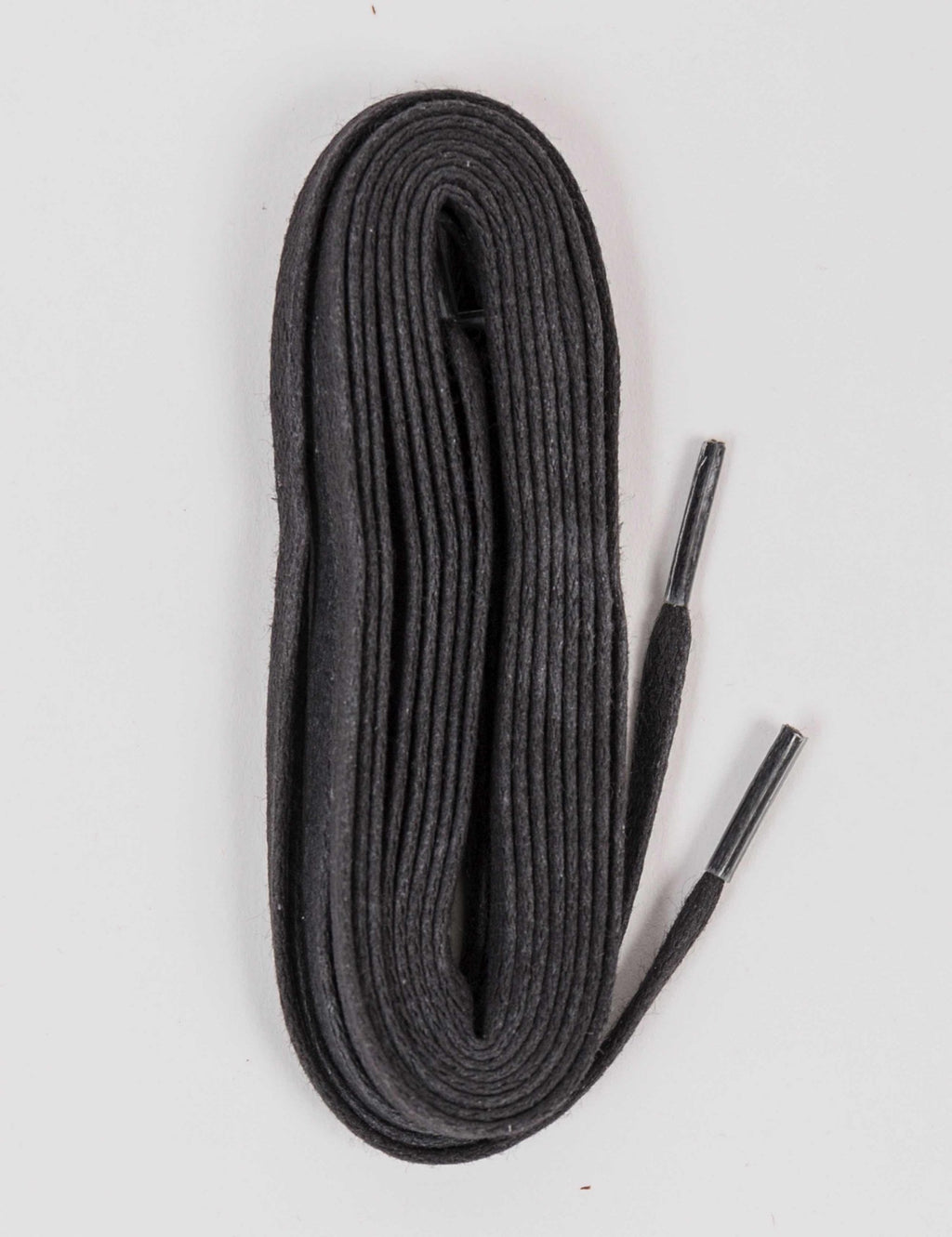 Black flat waxed boot laces coiled, showing smooth ribbed texture.