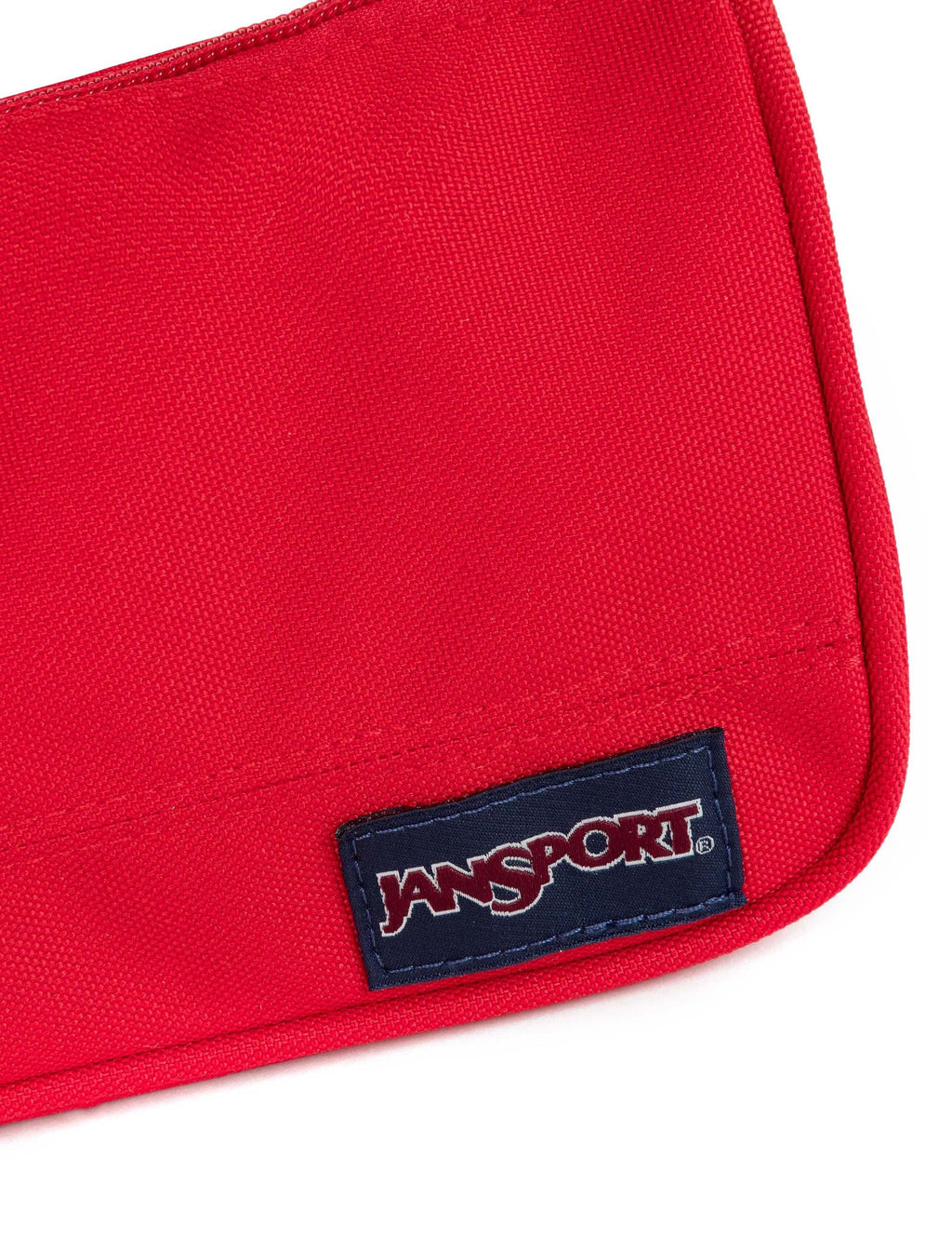 Medium accessory pouch close-up: red fabric with Jansport logo patch at corner seam.