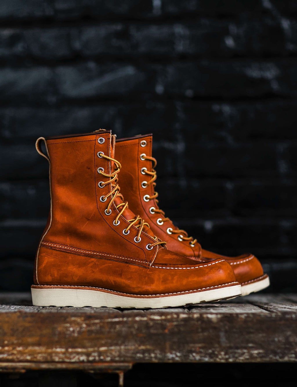 Rust-brown leather moc-toe boot with lace-up front and cream sole on display