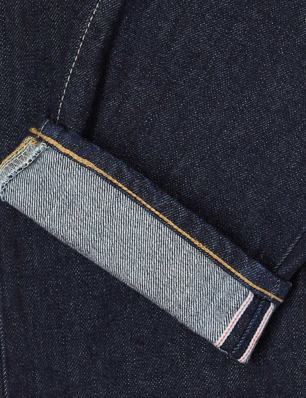 Jeans selvedge edge close-up with tan stitching and pink fabric label inside hem