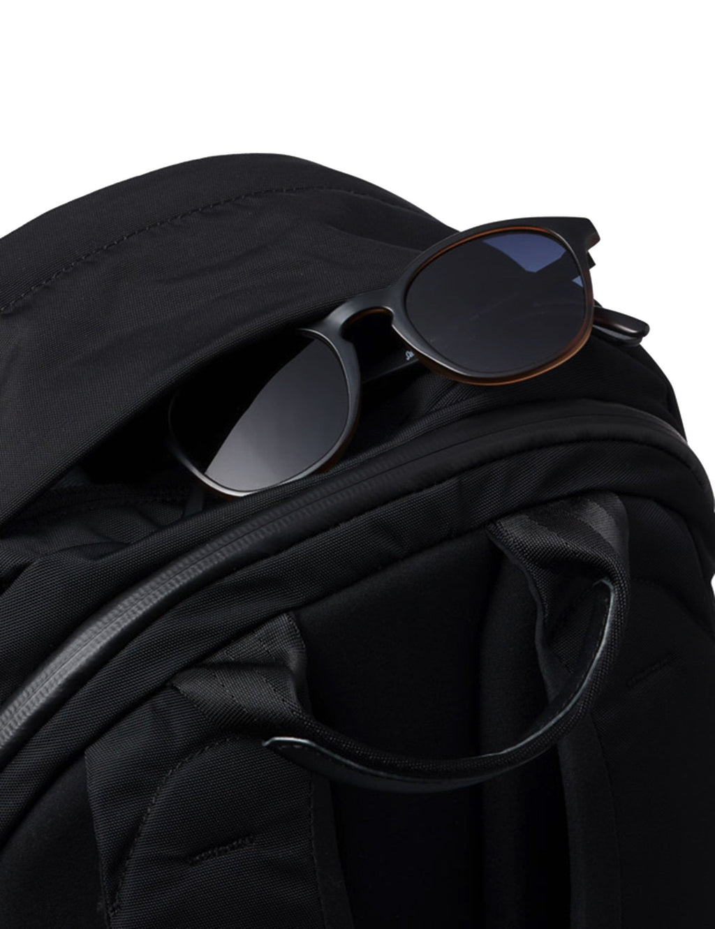 Black compact backpack with sunglasses resting on front pocket edge