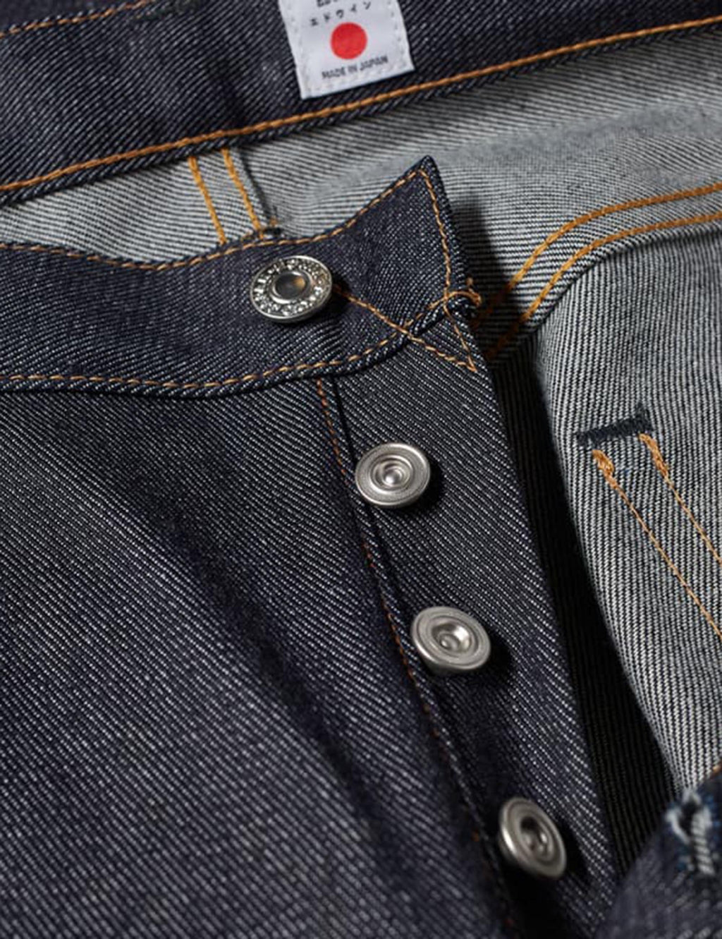 Men's jeans closeup: dark blue button fly, metal buttons and contrast orange stitching