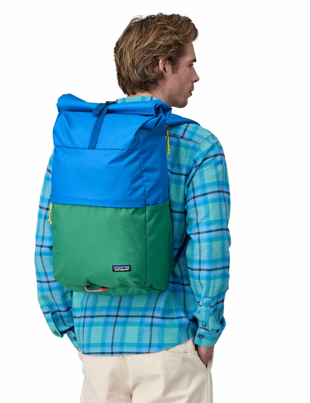 Roll-top backpack worn on back, blue top with green base and roll-top closure