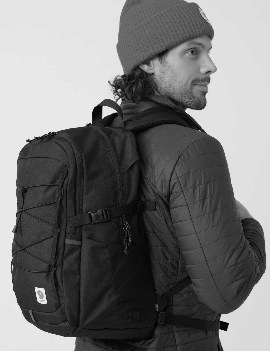 28L black backpack worn on shoulder, with side pocket and logo patch
