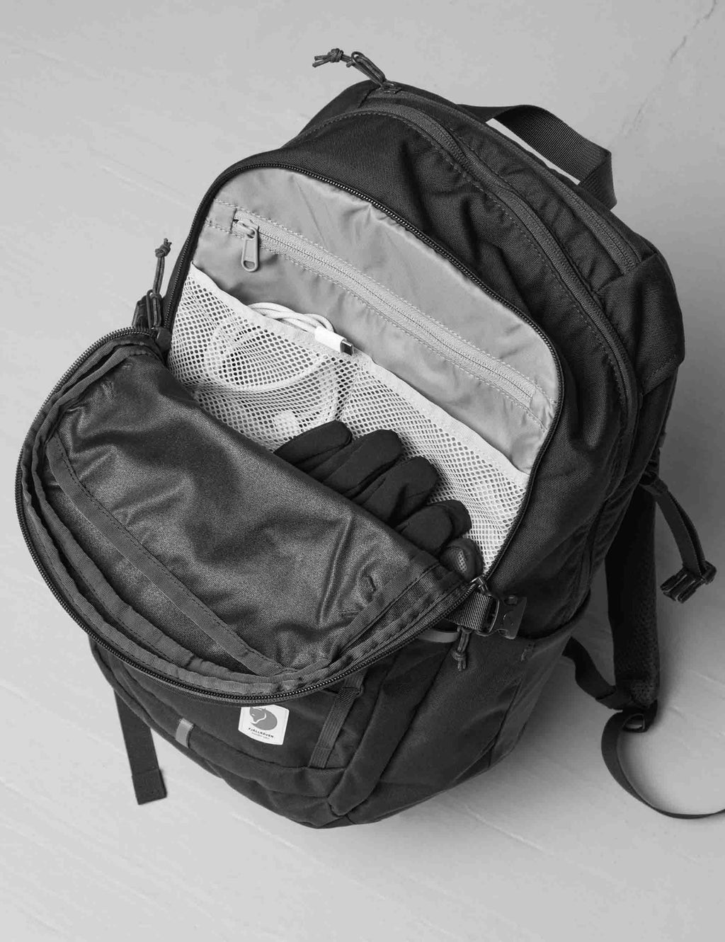 Navy 28L backpack open, showing internal zip compartments and sleeve divider