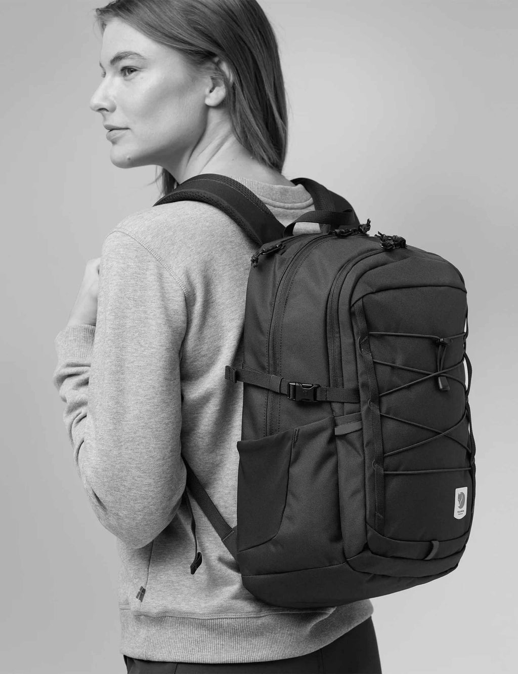 Black backpack worn on back with padded shoulder straps and front pockets