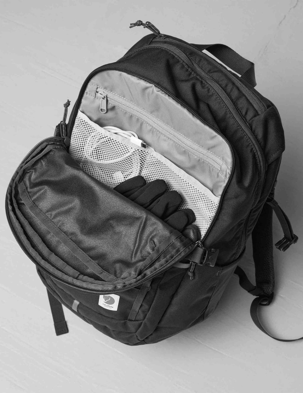 Black backpack opened to show mesh and zippered compartments