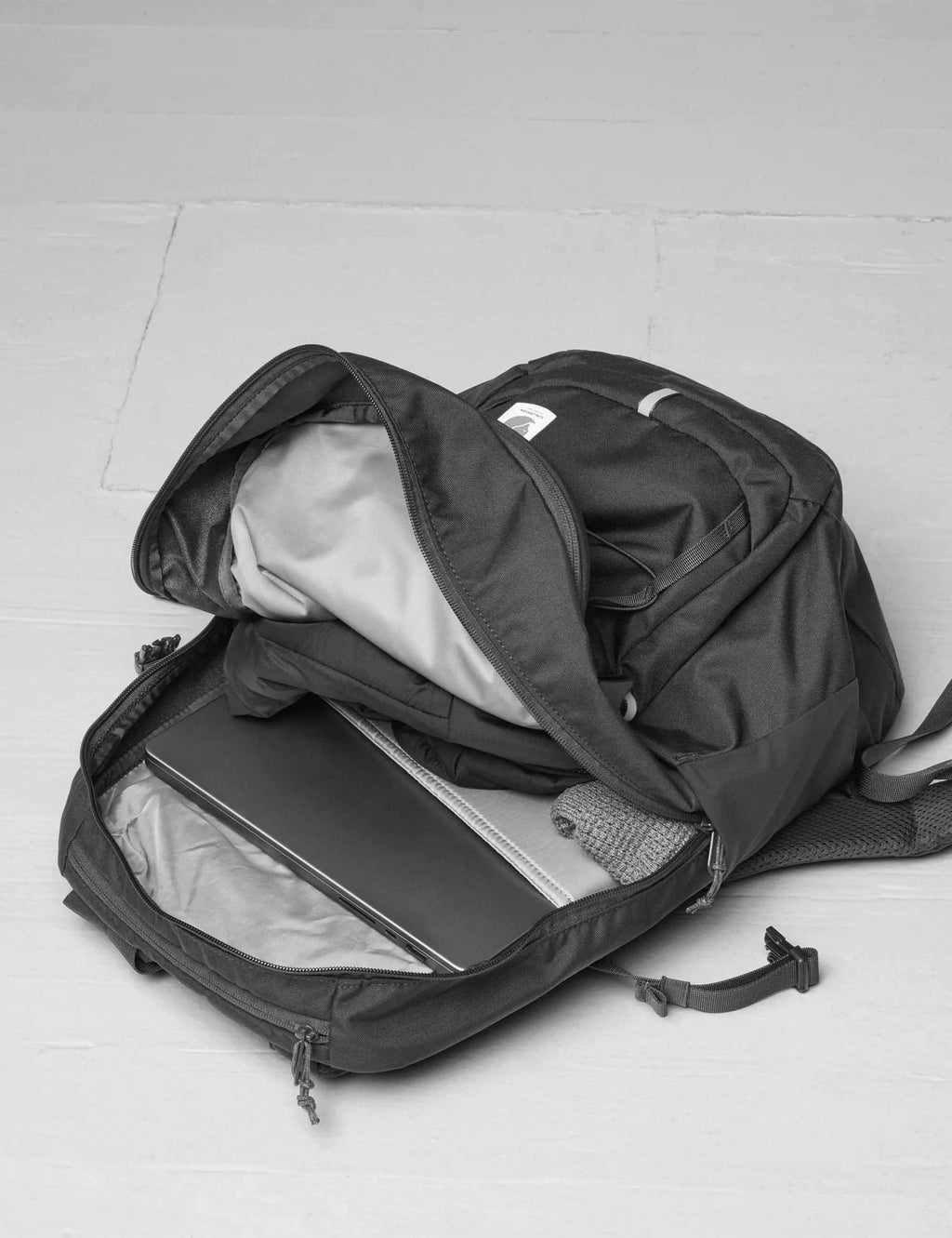 Black backpack with lid open showing inner zip compartments and mesh pocket