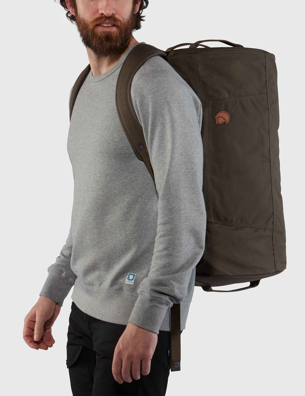 Dark olive travel bag side view with logo patch and shoulder strap.