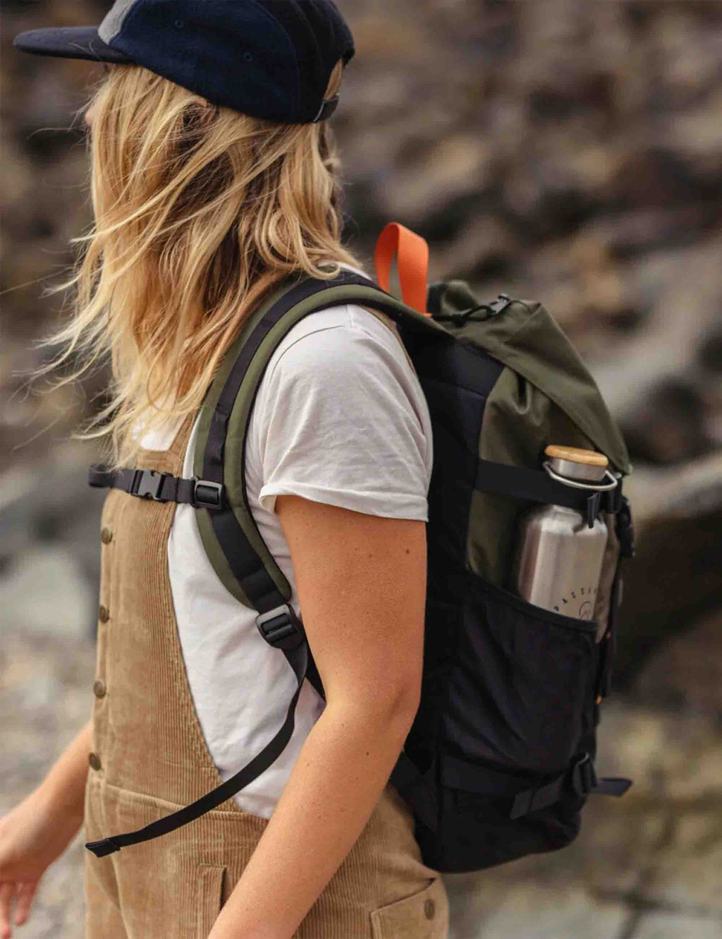 Recycled backpack worn on person, olive back panel with black straps and side bottle pocket