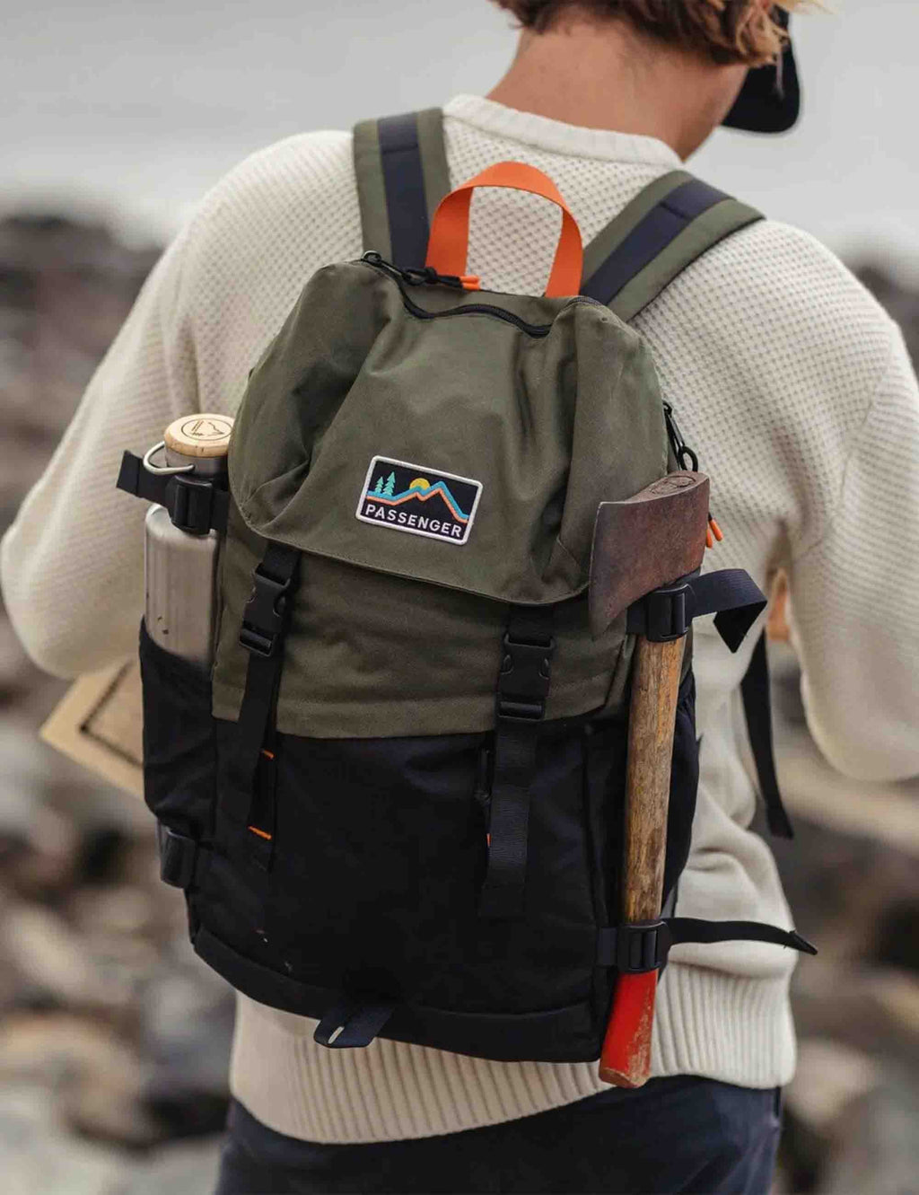 Recycled backpack worn on person, olive fabric with black straps, front logo patch, and side bottle pocket