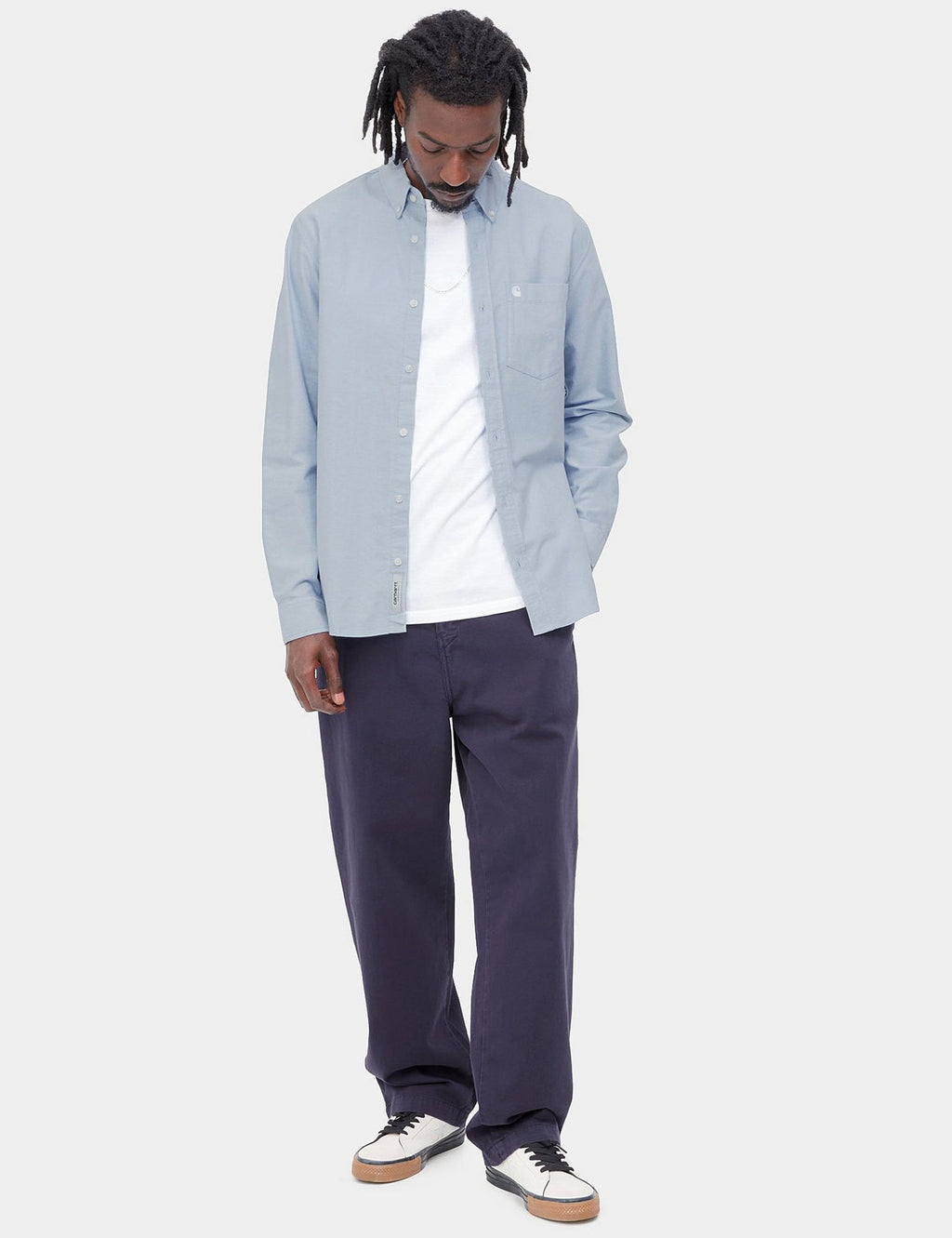 Light blue button-up shirt with long sleeves and chest pocket, styled with dark trousers