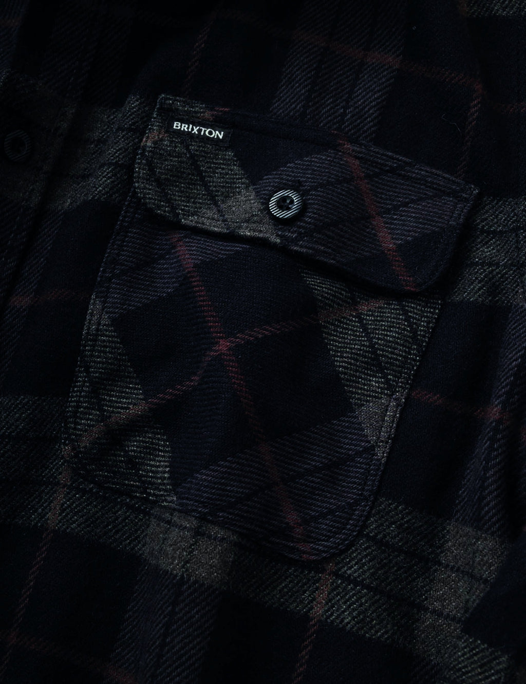 Dark plaid flannel shirt chest pocket with button and visible interior label