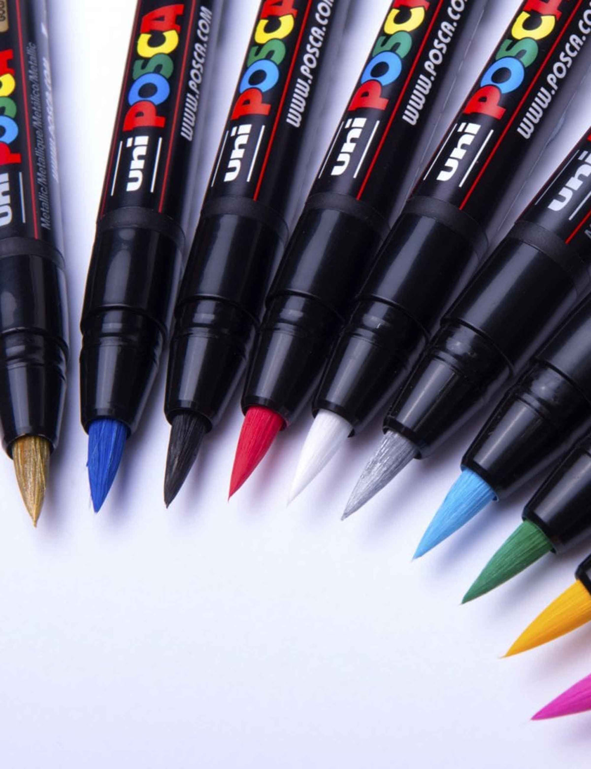 Brush paint pens lineup with pointed tips and color caps, including red