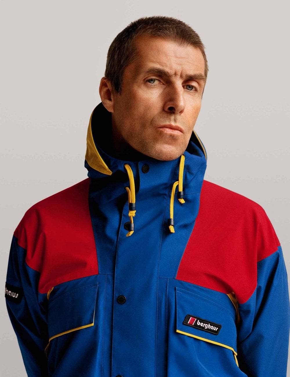 Waterproof jacket with hood, blue center with red shoulders, yellow drawcord