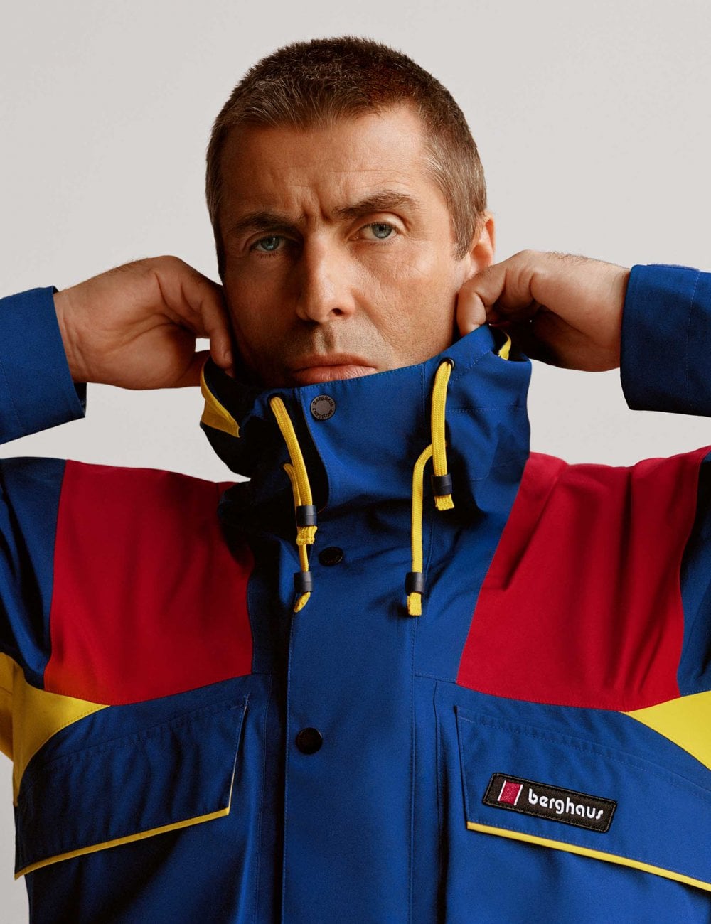 Waterproof jacket with hood, blue and red panels, yellow drawcord and chest pocket
