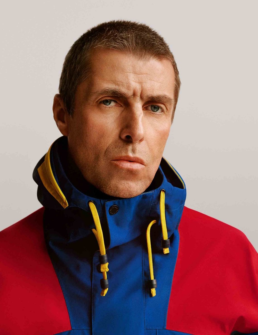Waterproof jacket with hood, blue and red panels, yellow-trim drawcord at collar