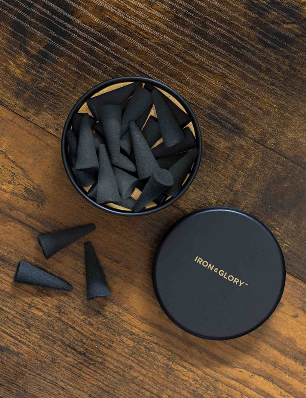 Sandalwood incense cones in open tin with loose cones and round closed lid on wood