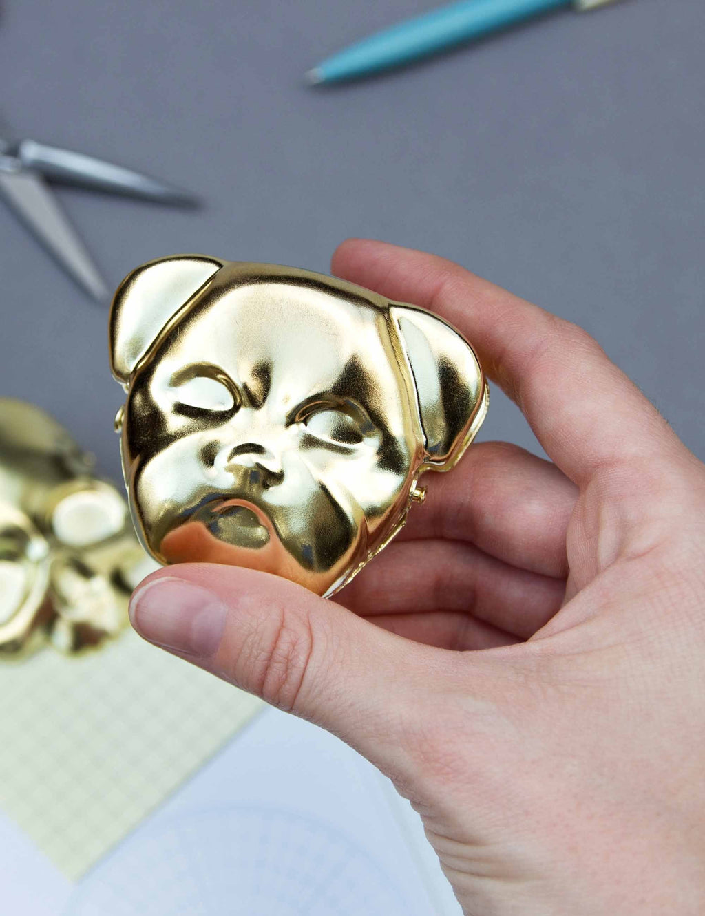 Brass bulldog clip, dog-face head with hinged jaw, held in hand