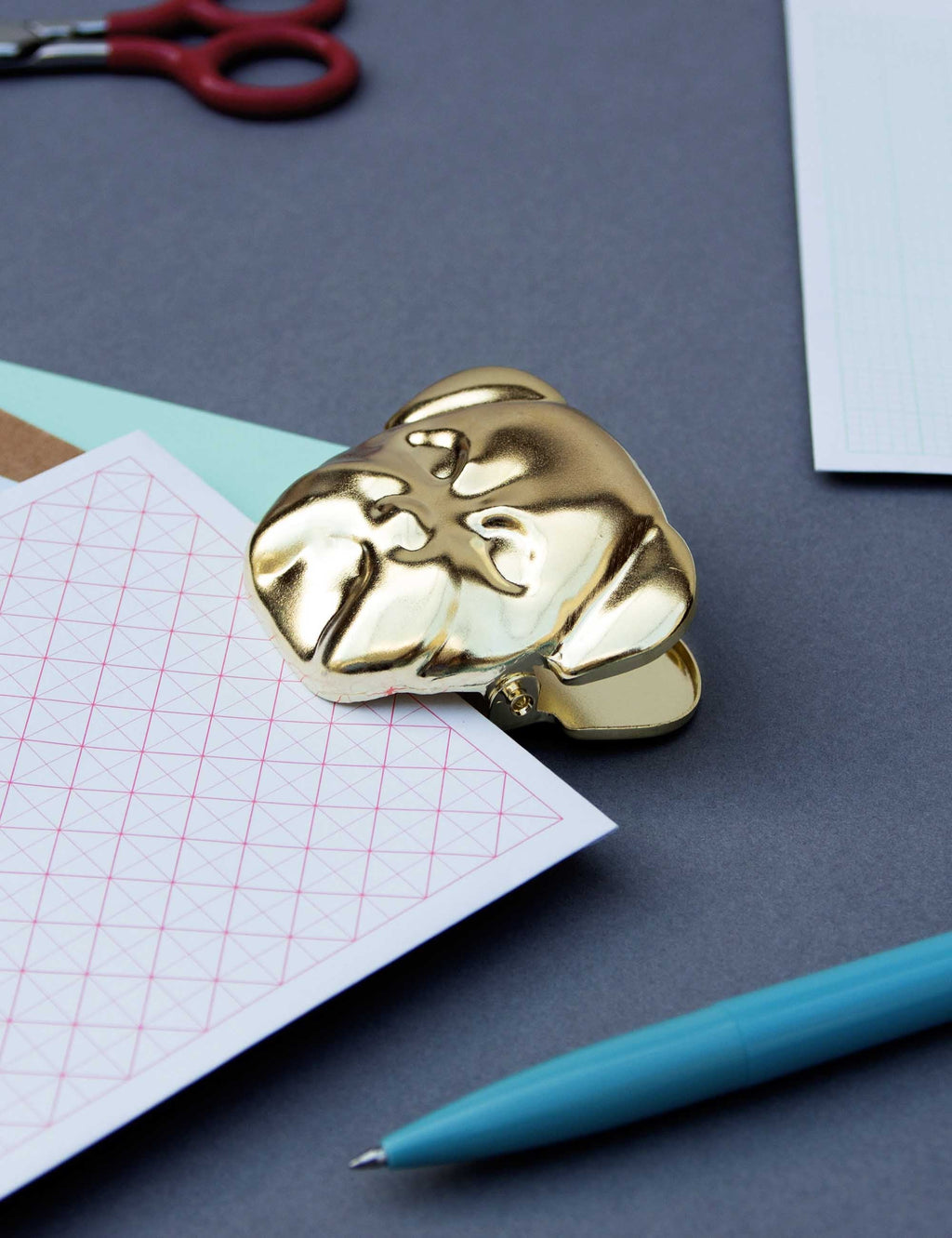 Gold bulldog metal clip lying on surface, dog face with hinged jaw