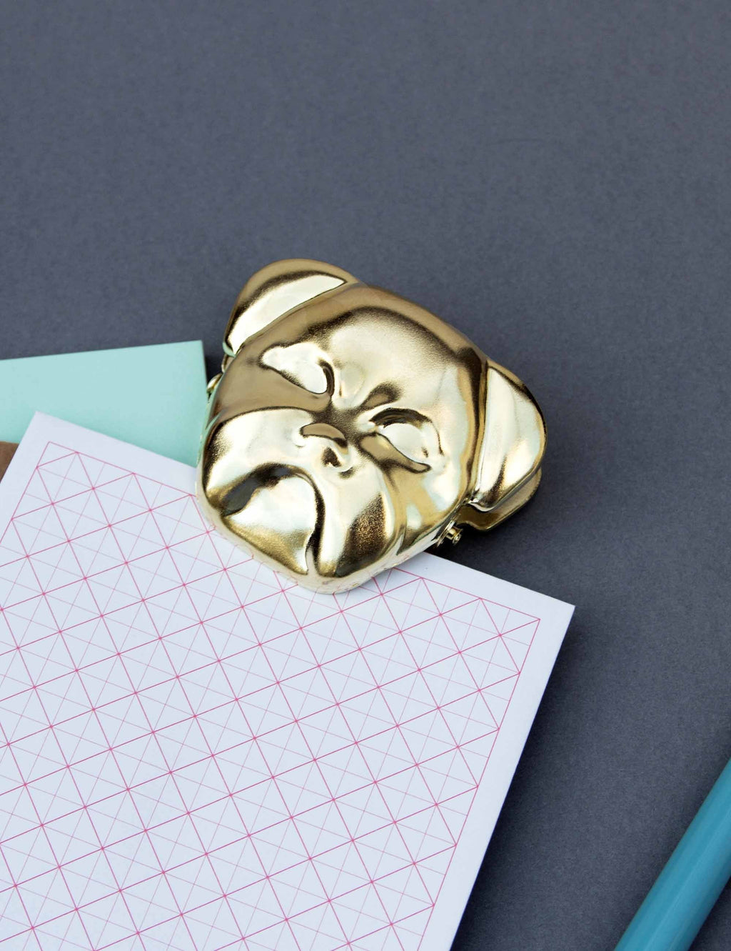 Gold bulldog clip on printed paper, dog-face top view