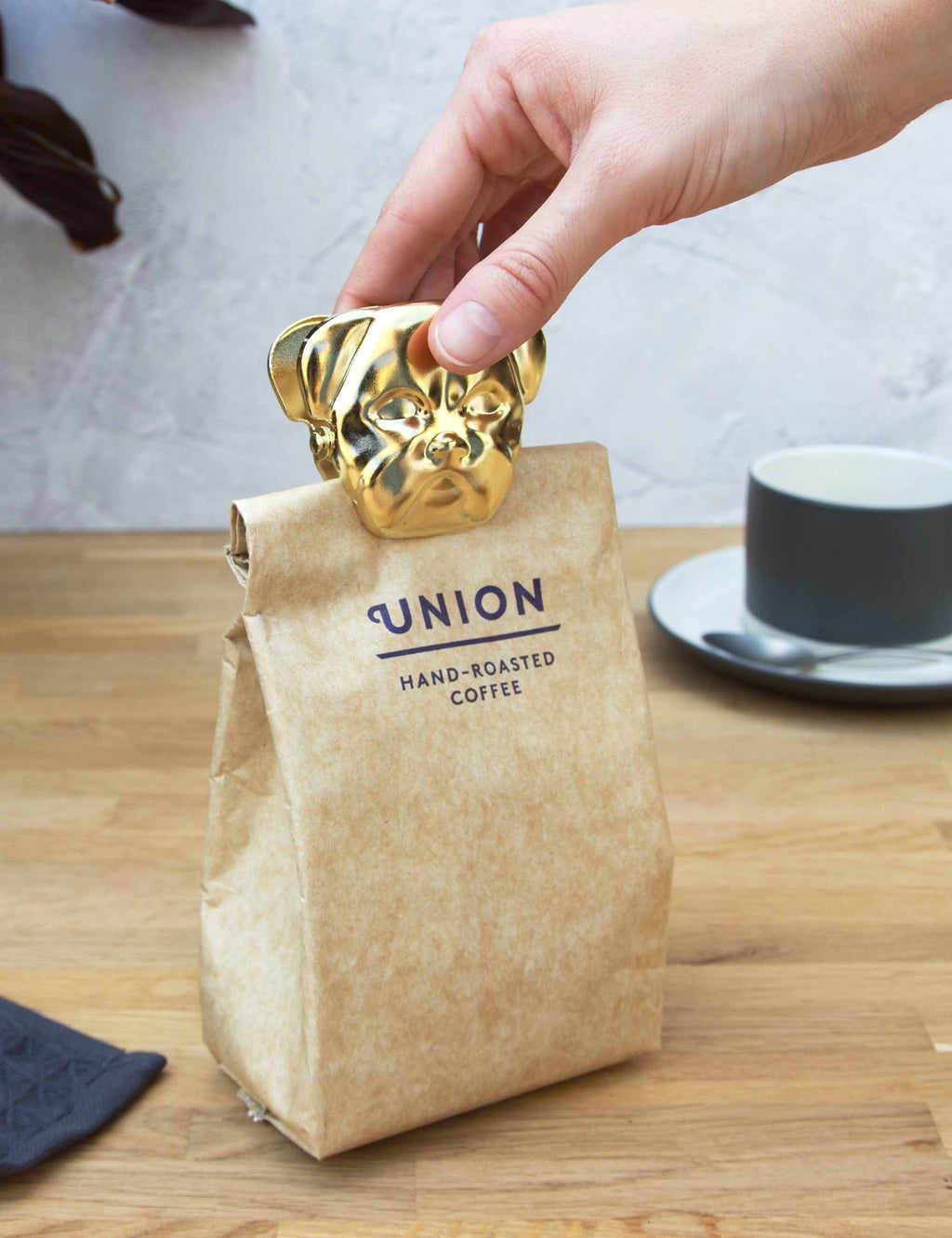 Gold bulldog metal clip on kraft paper bag, hand adjusting