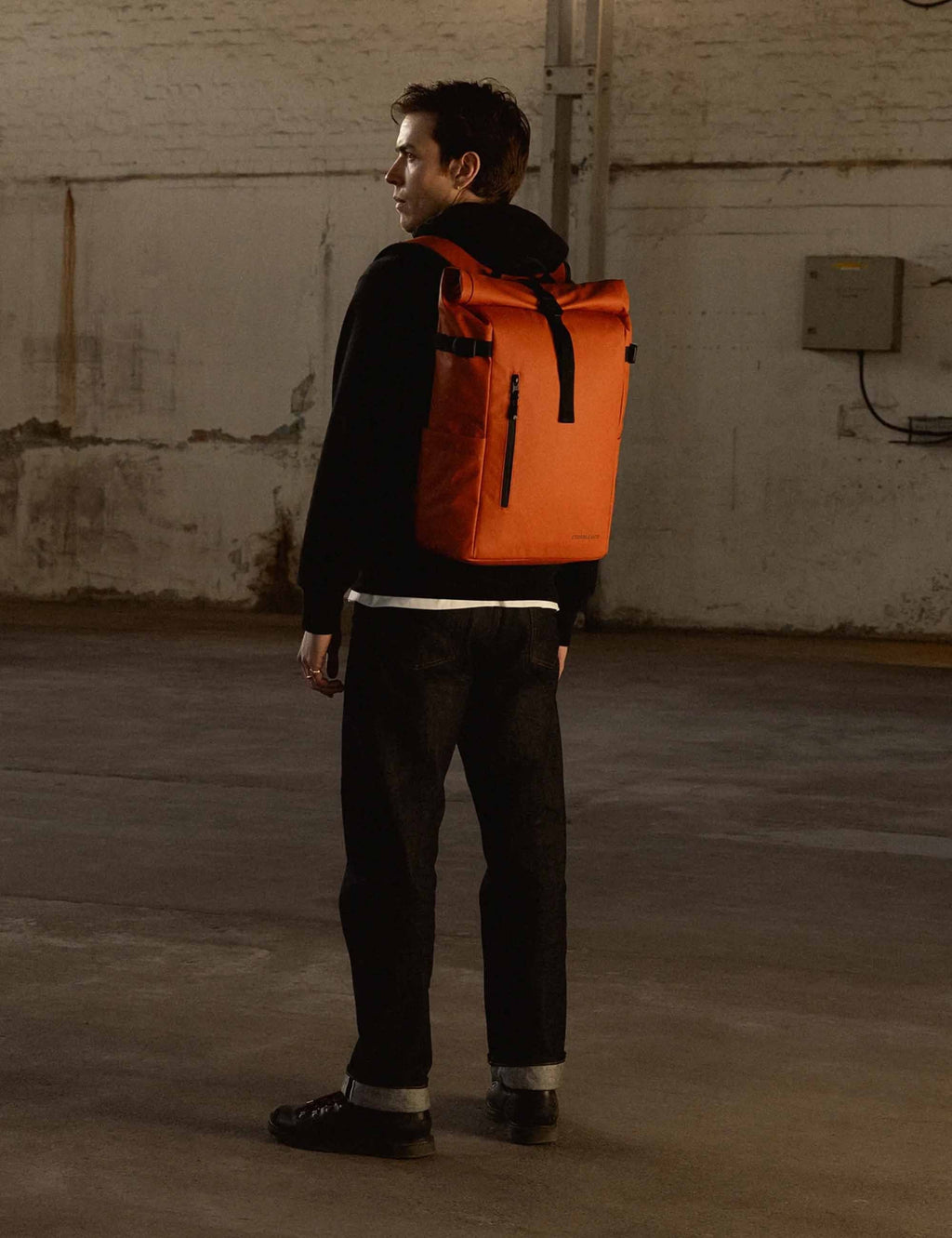 Rust roll-top backpack worn on back with black shoulder straps