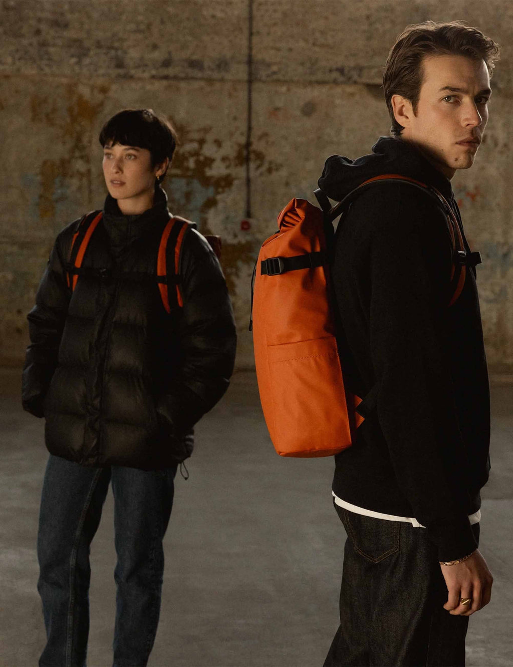 Rust roll-top backpack carried on back with black straps and front zip pocket