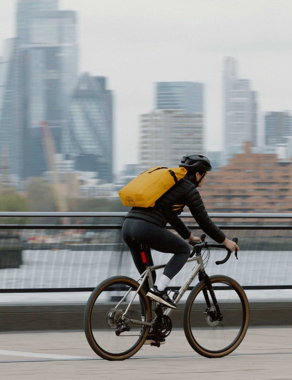 Yellow roll-top backpack on a cyclist, strapped with black harness