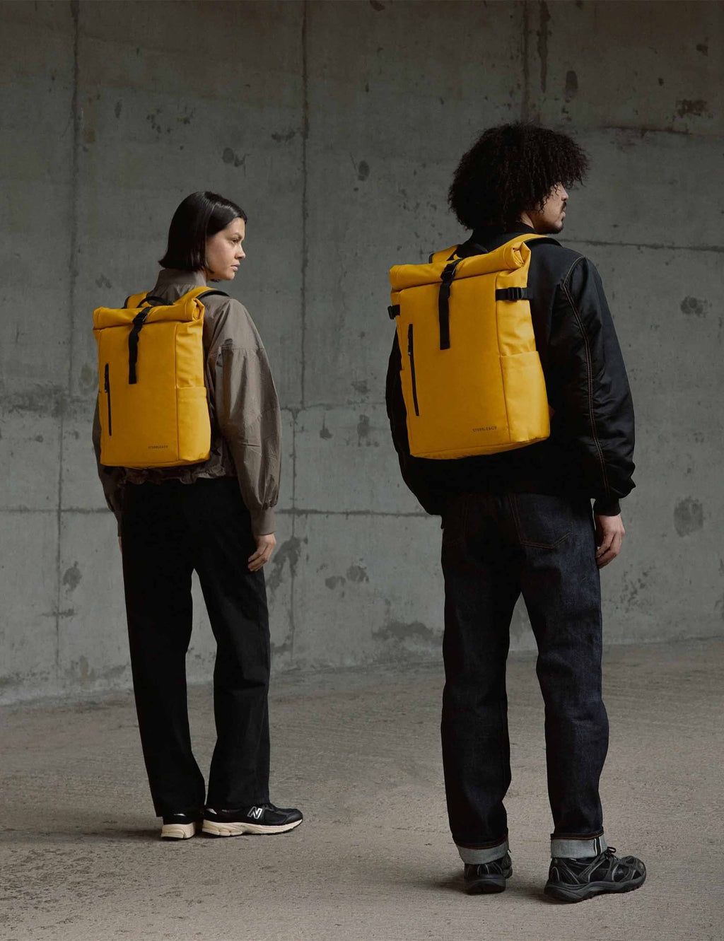 Yellow roll-top backpack worn on back with black straps and top roll.