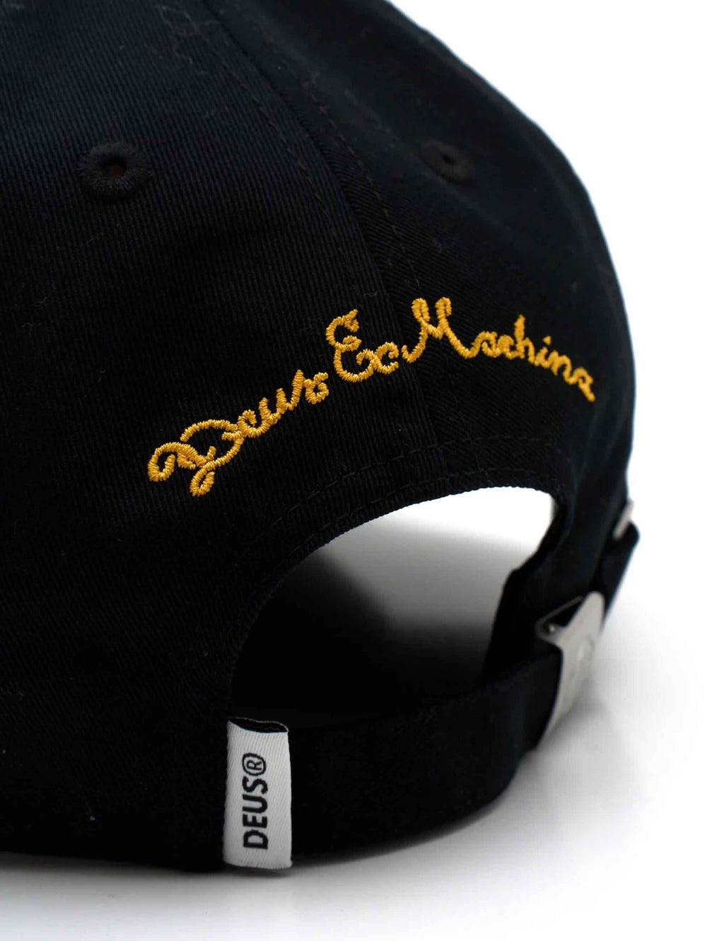Black baseball cap showing gold side embroidery and DEUS fabric tag