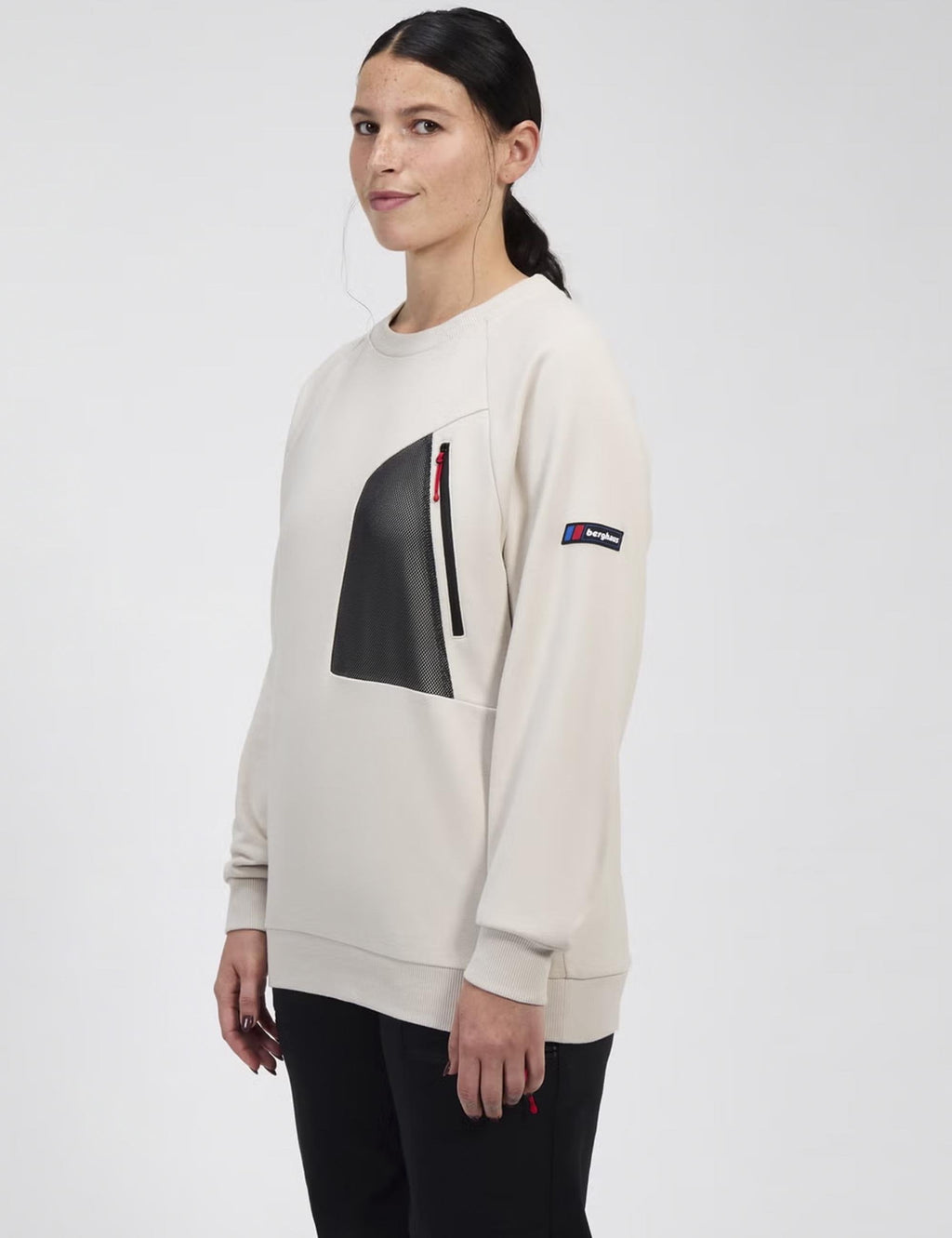 Crewneck sweatshirt side view with dark patch on front and logo accent on sleeve.