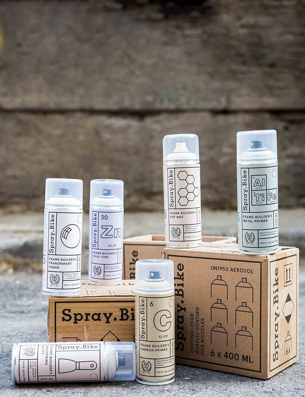 Assorted metal primer spray cans and boxes on ground, light grey tones