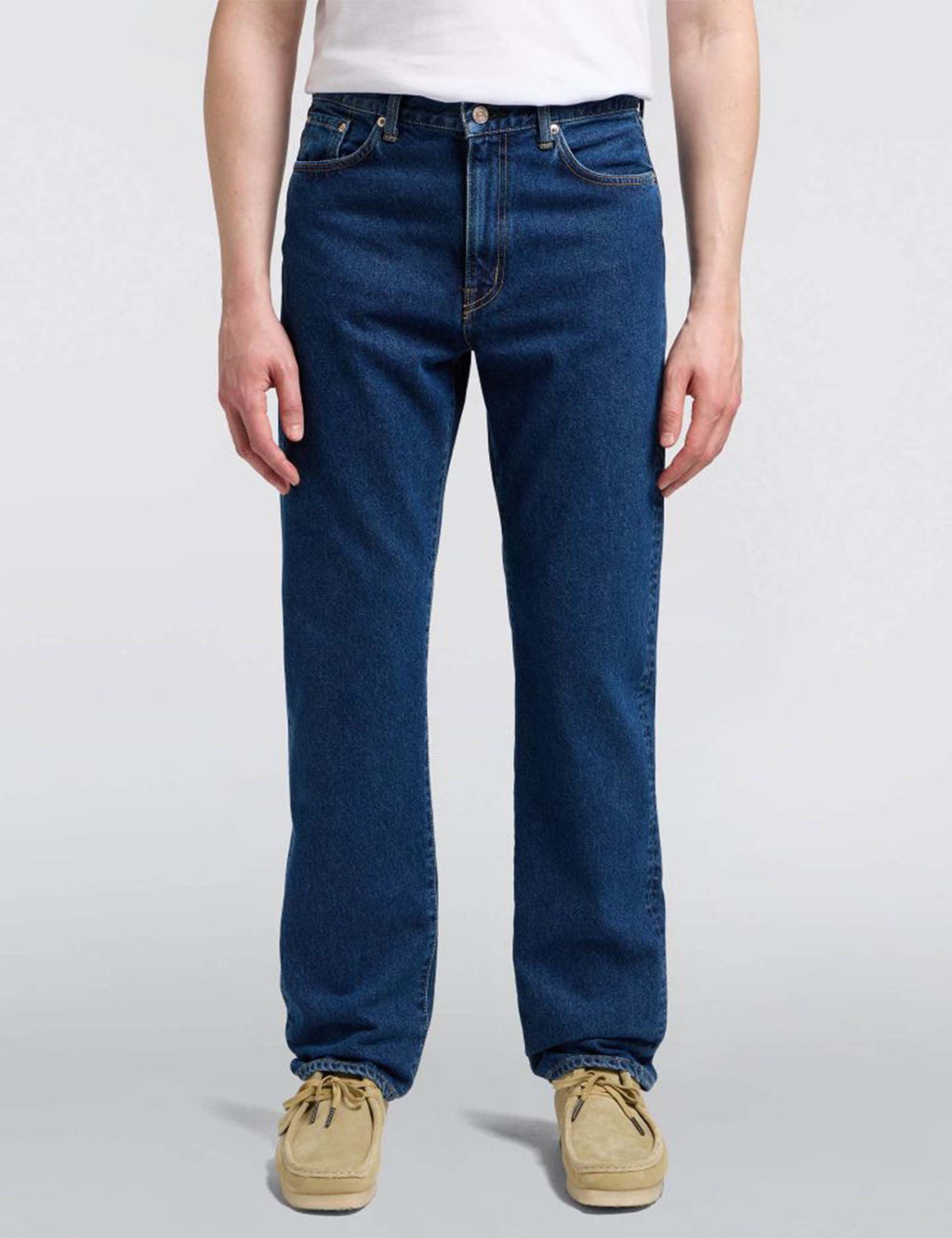 Mid-wash blue straight jeans on model, cuffed hem, five-pocket styling