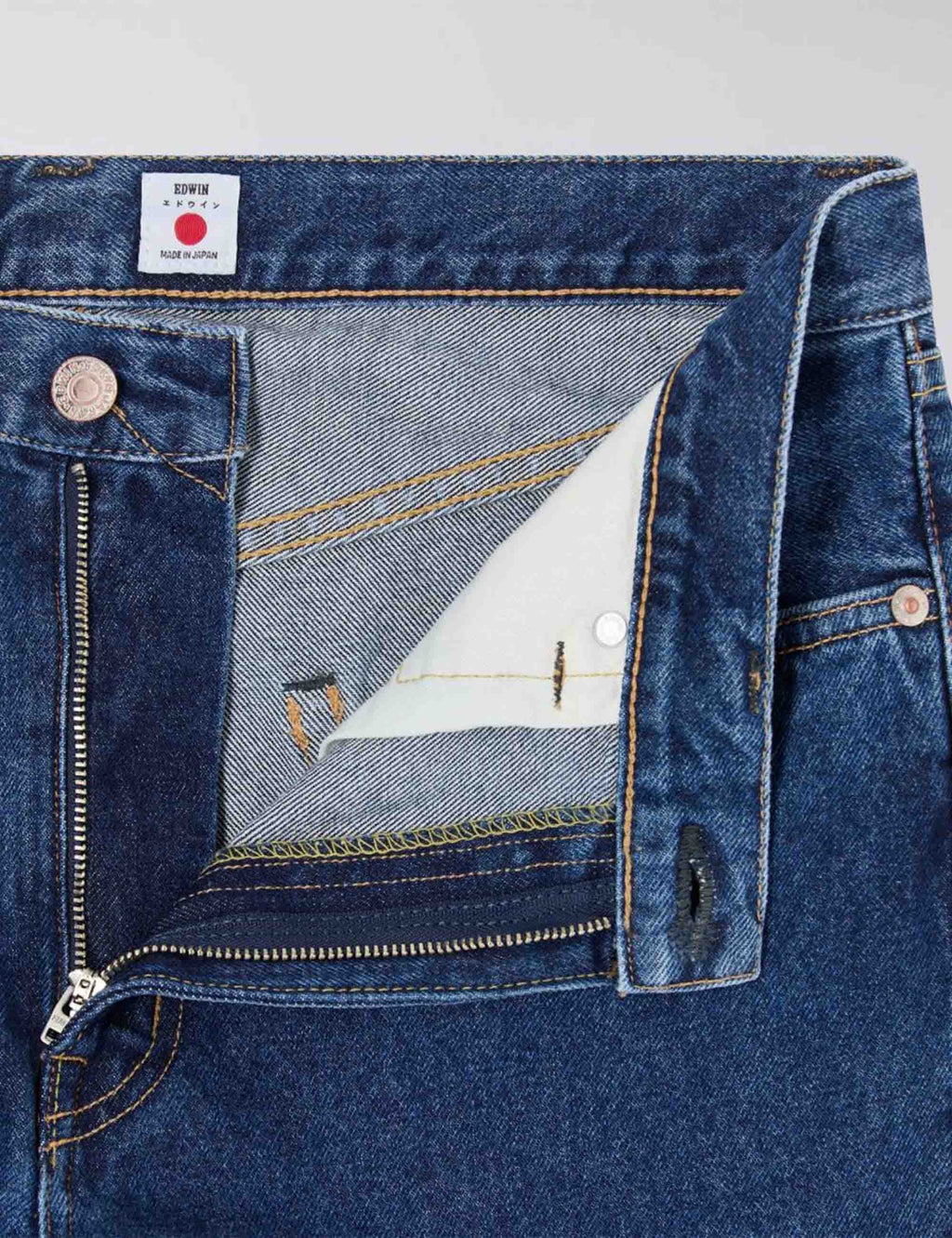 Mid-wash blue jeans, close-up of front pocket seam and metal button
