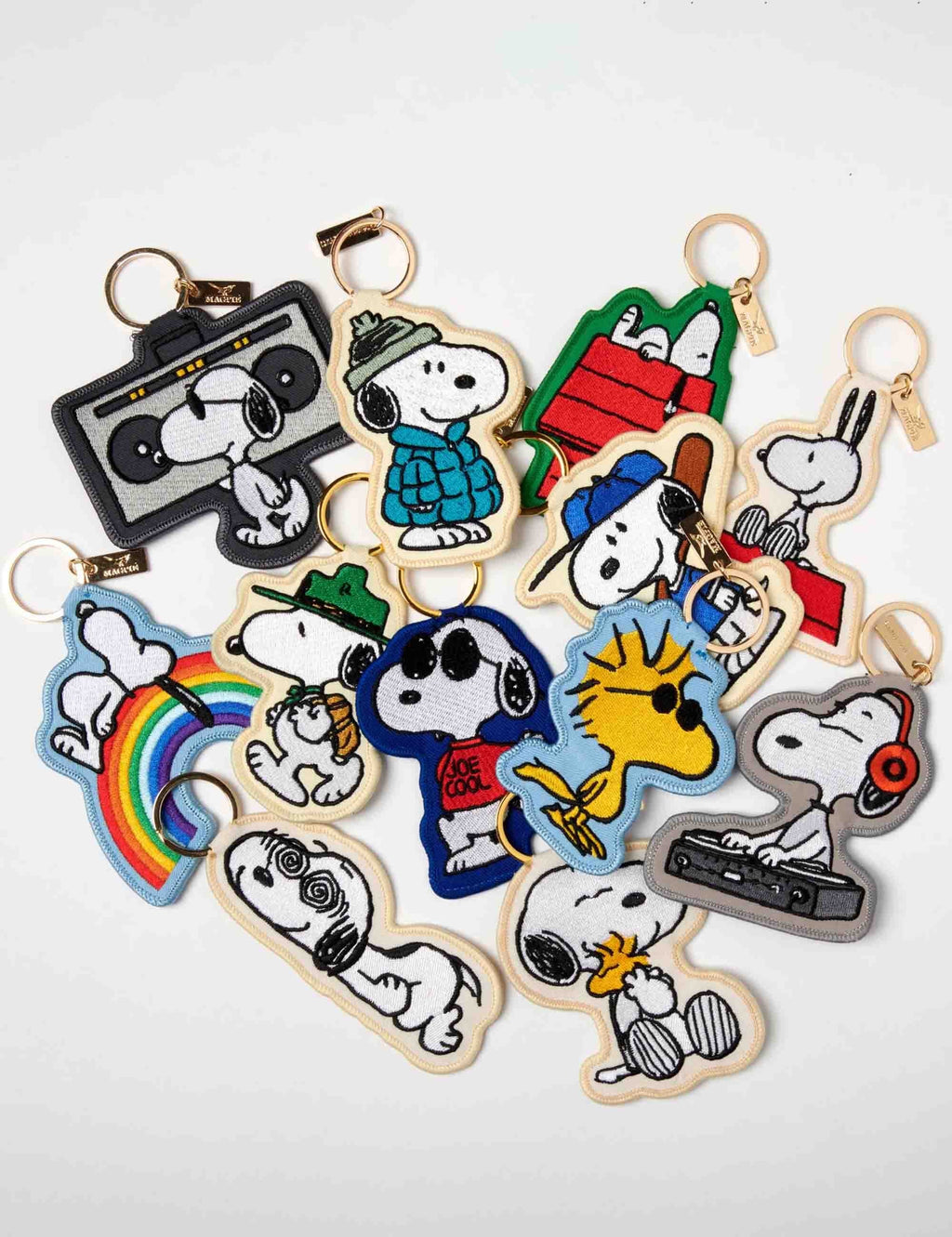 Assorted Snoopy key charms with gold-tone rings, featuring multiple character designs