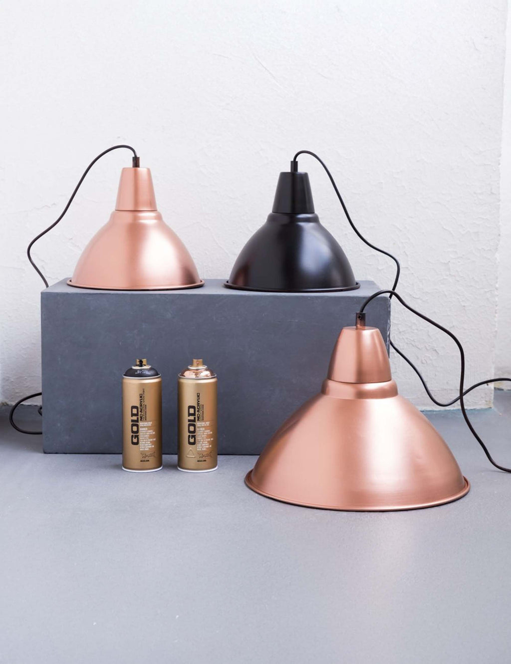 Copper chrome spray paint can set on board, with two hanging lamps in copper tones