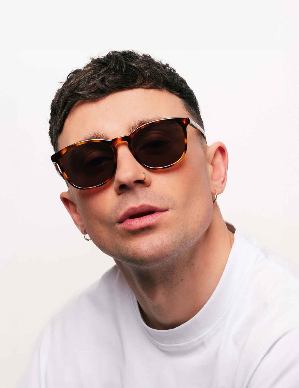 Brown-tinted sunglasses on a person, tortoise-brown frames, front view