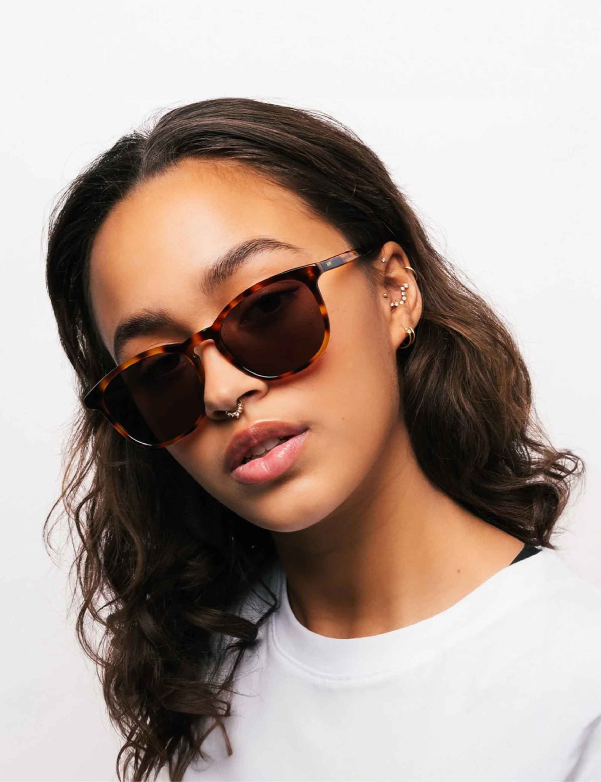 Brown-tinted sunglasses on a person, tortoise-brown frames, angled side view